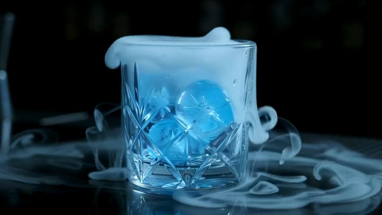 Blue ice spheres in a crystal glass with cold vapor spilling over the rim